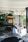 Hanging chair made of rattan on a covered terrace with plants