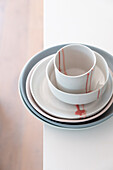 Stacked ceramic crockery on a light-coloured surface with red colour accents