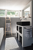 Modern bathroom with ladder towel rail and black washbasin