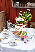 Etagere with pastries and sandwiches on a laid table in the garden