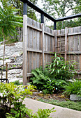 Corner garden area with wooden privacy screen and various green plants