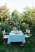 Laid garden table with pastries and flowers in a summer garden setting