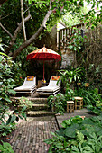 Romantic seating area with deckchairs and parasol in the lush garden