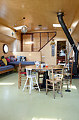 Bright dining area in houseboat with wood-burning stove and rustic furniture