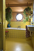 Bathroom with yellow tiles, round porthole window and hanging plants