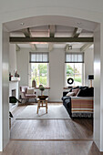 Living room with wooden beamed ceiling and large windows, grey and pink accents