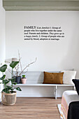 Scandinavian living room with wooden bench, plant and wall slogan