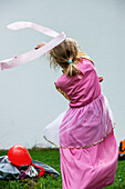 Child in princess dress dances with a swing band in the garden