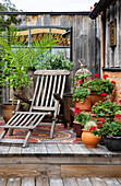 Cosy terrace with wooden lounger, geraniums and potted plants