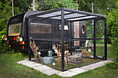 Chicken coop in modern cage next to renovated camper in the garden