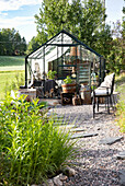 Path of gravel and stone slabs leads to greenhouse in the garden