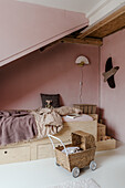 Children's room with wooden bed and pink walls, basket stroller and wall decoration