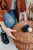 Person arranges a woven basket lid with three colourful pompoms