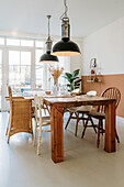 Dining room with wooden table, mixed chairs and plants in the background