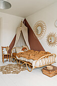 Rattan bed with canopy and mirror in bedroom with brown accent wall