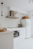 Modern white kitchen with integrated oven and retro fridge