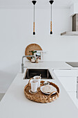 Modern kitchen with white worktop, sink and rattan tray