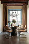 Dining area with round table and cantilever chairs in front of floor-to-ceiling window