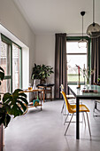 Dining room with yellow chair, plants and large windows