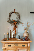 Wooden chest of drawers with rustic decor: dried flowers, candles and retro camera