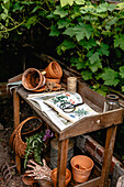 Planting table in the garden with clay pots, books and scissors