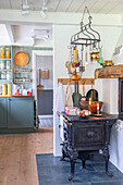 Vintage cooker, hanging kitchen utensils and candles in cosy country kitchen