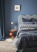 Blue bedroom with patterned headboard and designer wooden table