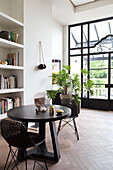 Round wooden table with black rattan chairs in the light-flooded room