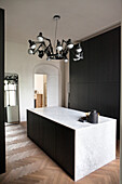 Marble kitchen island, herringbone parquet flooring and black ceiling light