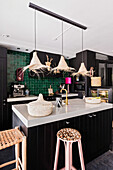 Kitchen with green tiled wall and pendant light made of straw hats