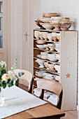 Open-plan dining area with rustic shelf full of ceramic crockery