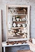 Mirror reflection of a rustic shelf with ceramic crockery and chandelier