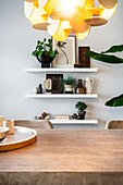 Dining room with wooden table and wall shelves with decorations and plants