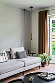 Living room with grey sofa, black side tables and open patio door