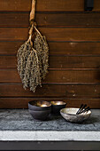 Holzwand mit hängenden Trockenblumen und Schalen auf Steintisch