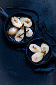 Pickled pear halves with vanilla pods in cast-iron pans