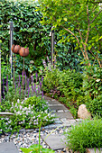 Natural stone path through lush garden with sculptures in the form of flowers