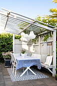 Arbor with table with blue table tablecloth and hanging lamps in the garden