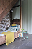 Sleeping alcove with natural stone wall under wooden staircase