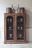 Vintage wooden cupboard with plant pots and decorative antlers