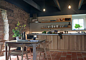 Dining area in rustic kitchen with natural stone wall and wooden furniture