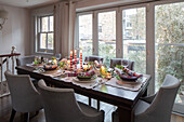 Festively laid dining table in front of large windows