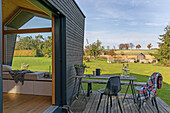 Terrace with wooden table and view of wide meadow landscape