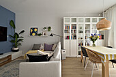 Bright living room with blue accent wall, glass cabinet and dining area