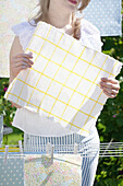 Woman hangs checkered oilcloth on washing line to dry