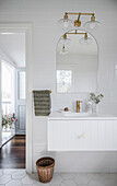 Bathroom with white tiled wall, golden fittings and large mirror