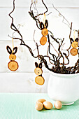 DIY Easter decoration: Bunny pendant made of wooden discs on branches in a white vase