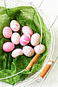 Painted Easter eggs in shades of pink and pink in a wire basket