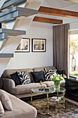 Living room with sofa corner, cushions with zebra pattern and glass tables, wooden beamed ceiling