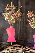 Pink-coloured dressmaker's dummy with dried flowers in a rustic setting